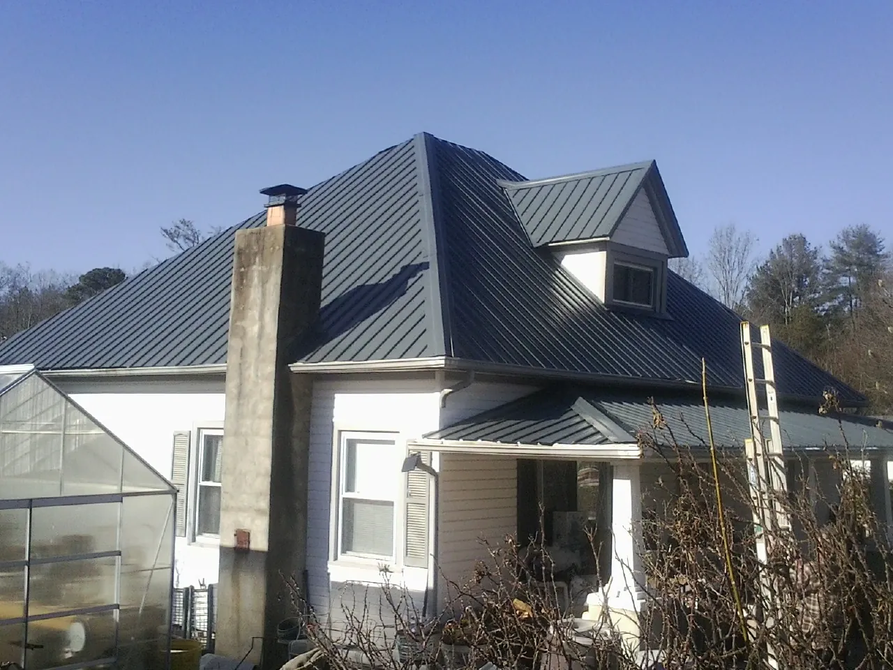 Dark blue standing seam metal roof on a white farmhouse with dormer — Slate & Tile Roof Repair by Roofing Brothers in Clackamas