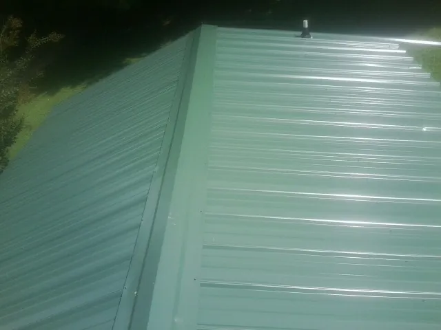 New green metal panels meeting at the ridge of a roof — Flat Roof Repair work by our crew in Clackamas