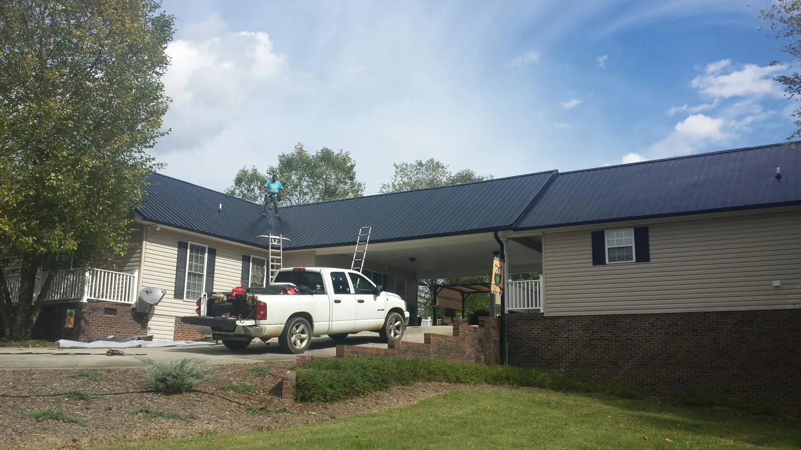 Black metal roof over a home and attached breezeway with ladders set in Clackamas