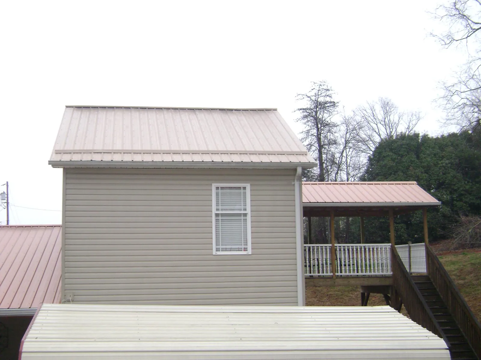 Tan metal roofs on a two story addition and attached porch, from a Roof Replacement job in Clackamas