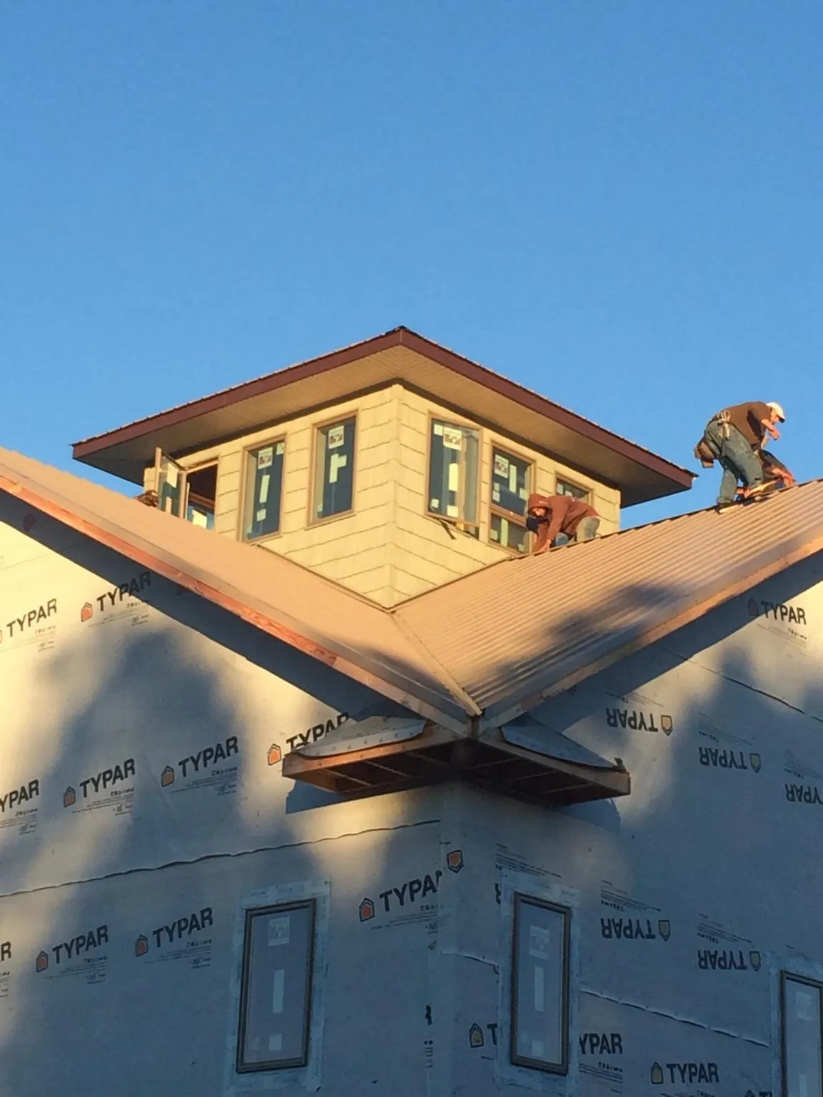 Roofers working around a rooftop cupola on a new metal roof at sunset — Roof Waterproofing in Clackamas by Roofing Brothers